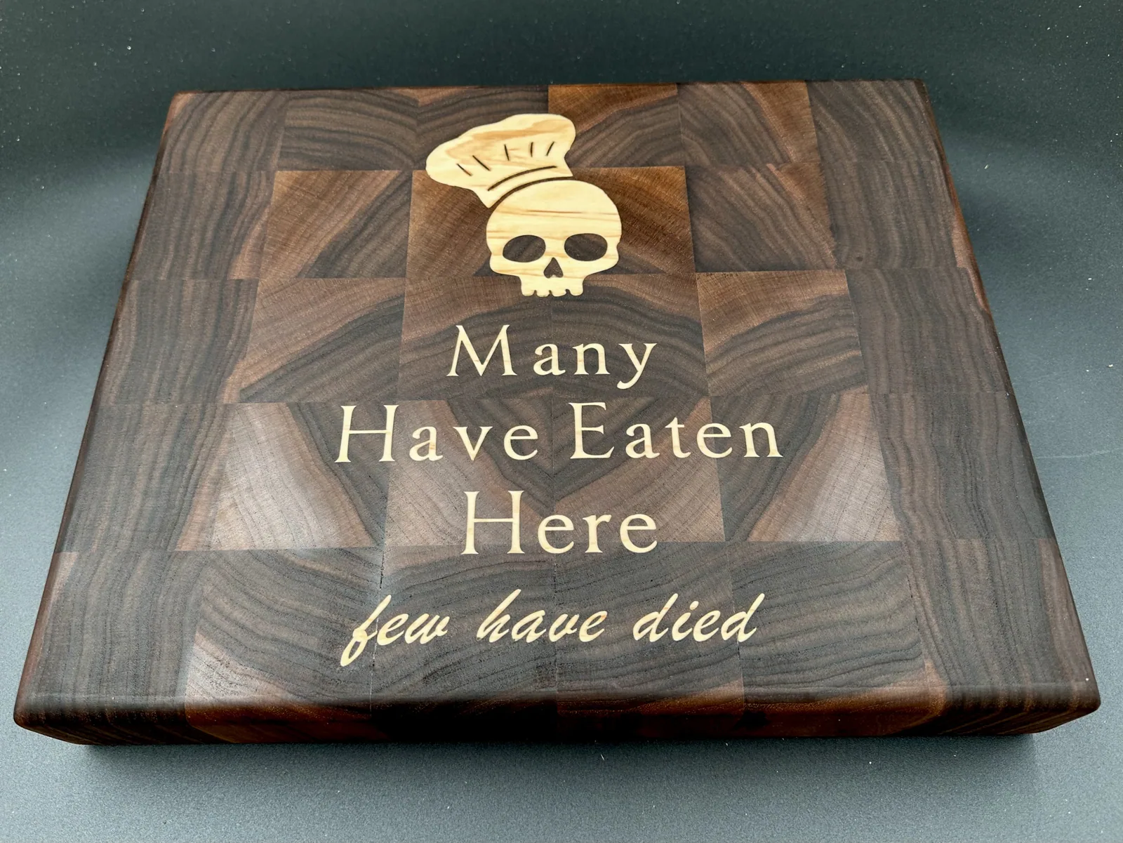 Engraved end-grain walnut cutting board with a maple inlay